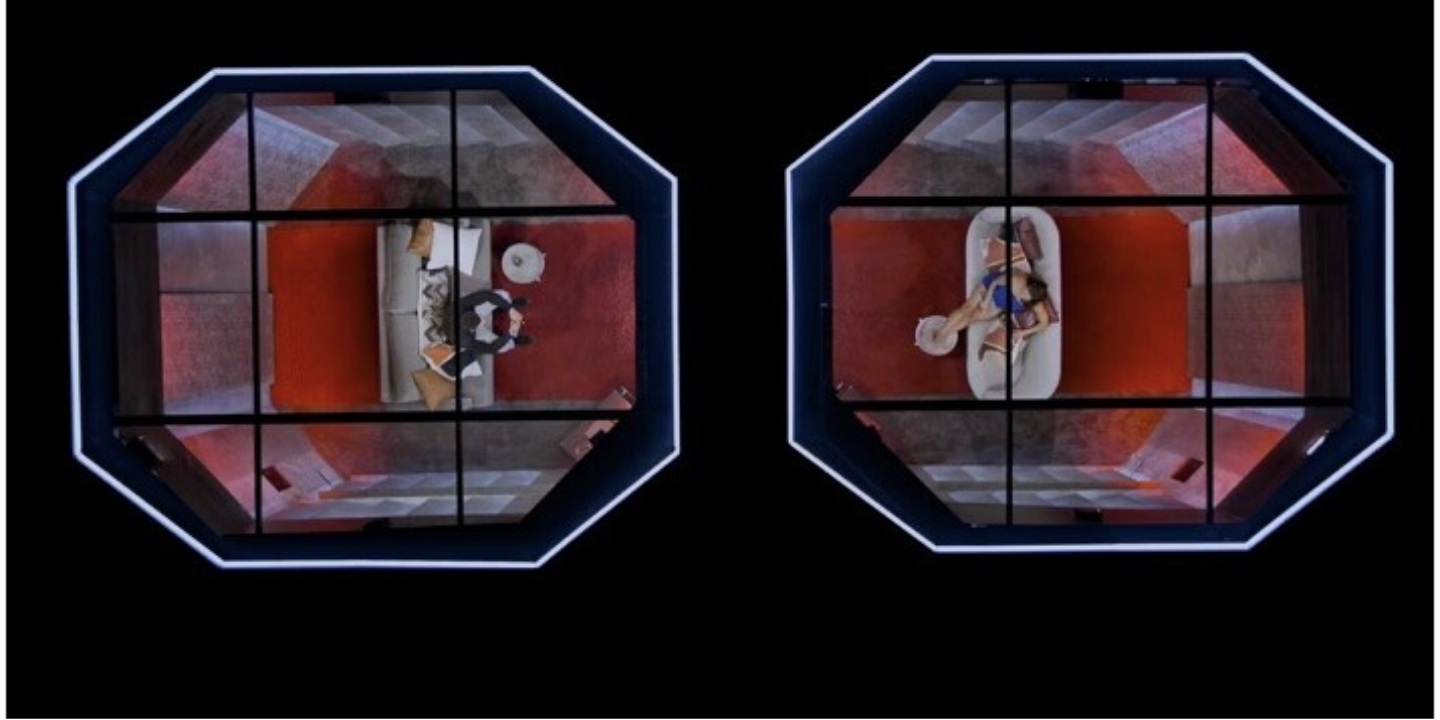 Netflix's Love is Blind pods. ID: Two octagon shaped rooms separated with a person sitting in each room. (image credit: TV Insider)