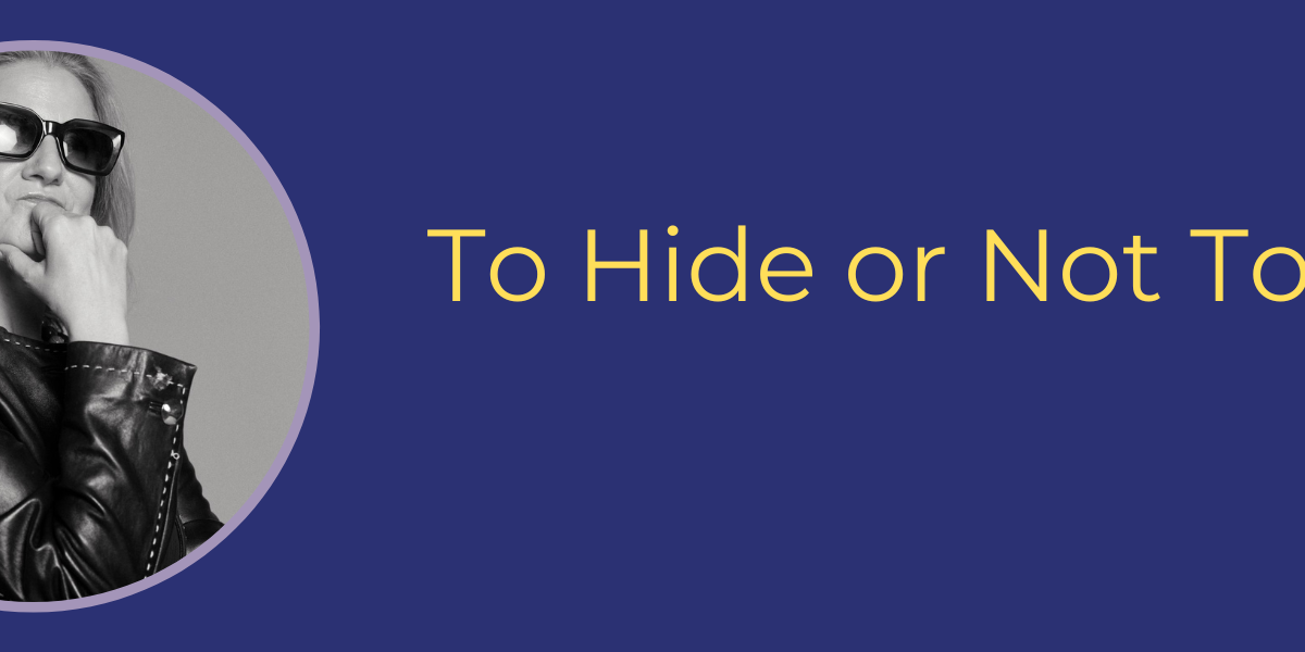 ID: B/W photo: white woman wearing sunglasses and a leather jacket. One hand rests on her chin. Words: To Hide or Not To Hide? (Photo by Molly Zacher)