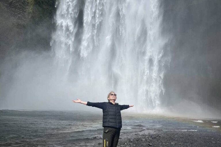 woman with arms outstretched at the skógafoss waterfall in Iceland.