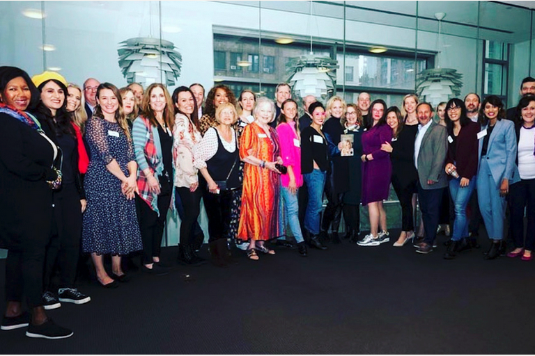 Group photo of people standing together at an NSA-NYC event, smiling toward the camera. Photo credit: John DeMato